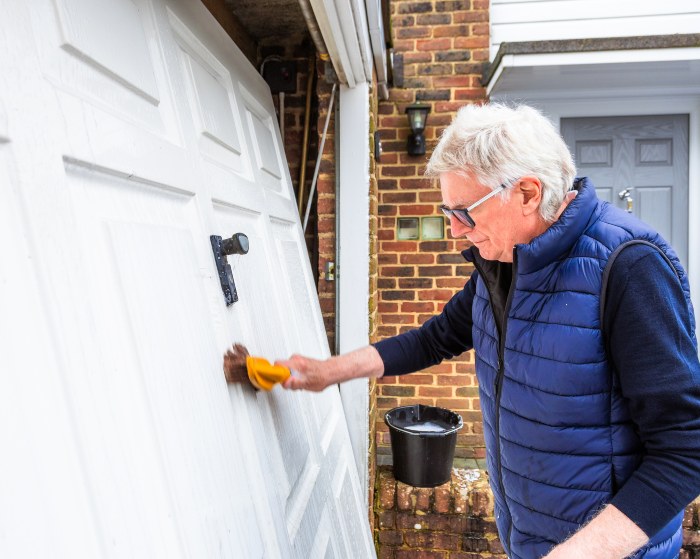 Man cleaning a white residential garage door with a brush at a home in Jacksonville, FL