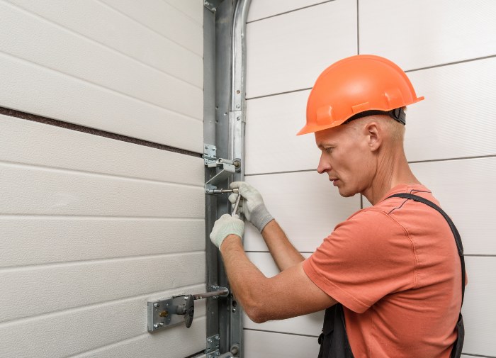 Worker inspecting and adjusting residential garage door hardware in Jacksonville, FL