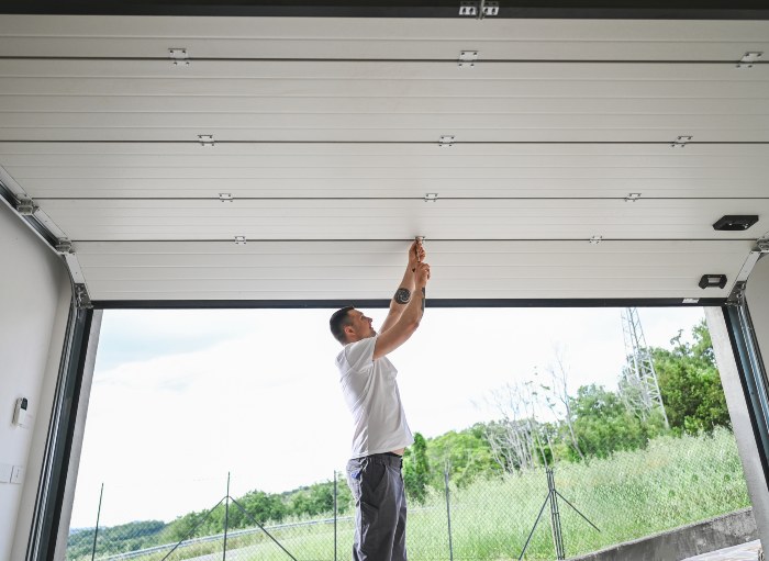 A professional is repairing the garage door with the help of a tool in Jacksonville, FL.