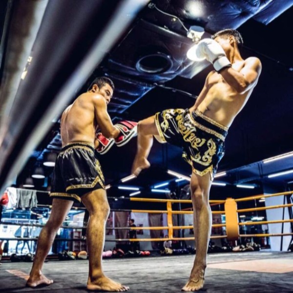 Two athletes are practicing Muay Thai in a boxing ring in Jacksonville, FL for fitness and self-defense training.