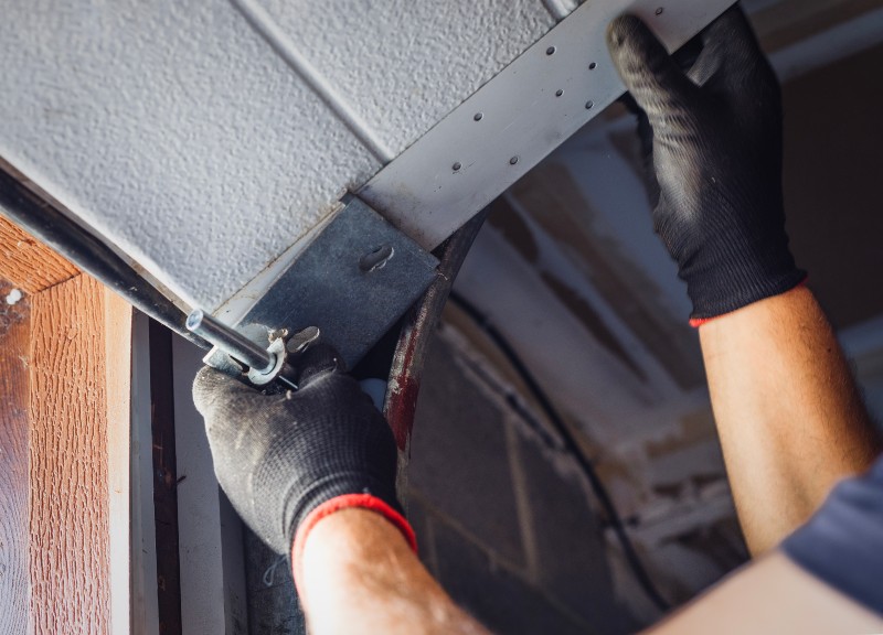 Garage door technician repairing track hardware and brackets in Jacksonville, FL