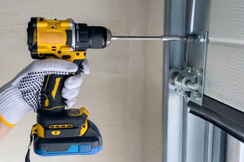 Professional installing garage door hardware with power drill in Jacksonville, FL