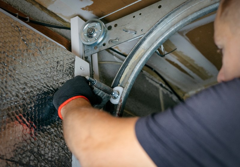 Garage door technician replacing roller on track system in Jacksonville, FL